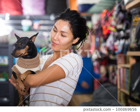 Portrait of smiling woman with his dog in winter clothes visiting pet supplies shop Portrait of smiling woman with his dog in winter clothes visiting pet supplies shop 100869656