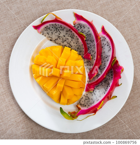Plate of slices of ripe sweet and juicy mango and pitaya 100869756