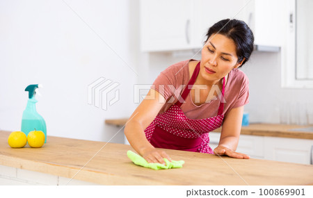 Woman cleaning table with rag at home Woman cleaning table with rag at home 100869901