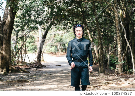 Male runner walking through trees on trail run Male runner walking through trees on trail run 100874557