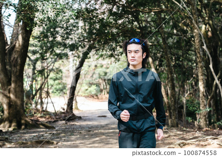 Male runner walking through trees on trail run Male runner walking through trees on trail run 100874558