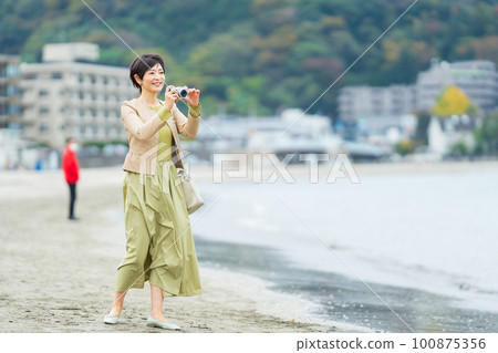 Middle-aged woman taking pictures on a trip 100875356