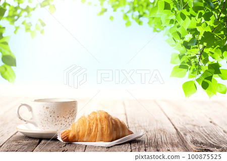 Coffee cup and croissant on wooden table Coffee cup and croissant on wooden table 100875525