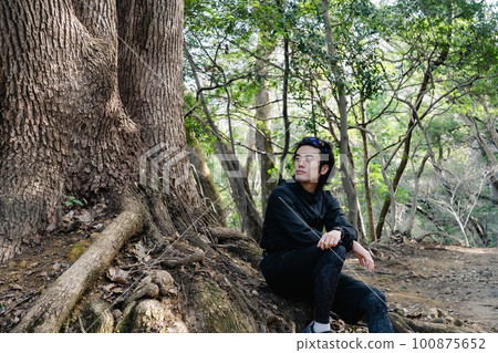 坐在一棵大樹的基地的男性賽跑者 100875652