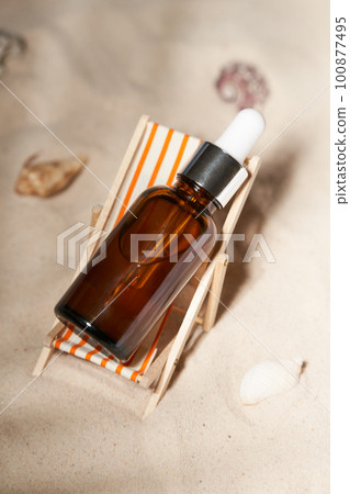Summer sunscreen essence in deck chair on the sand backgroundwith shells ans seastar. B Summer sunscreen essence in deck chair on the sand backgroundwith shells ans seastar. B 100877495