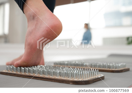 A woman comes down from the sadhu boards. Close-up of feet with prints after nails.  100877569