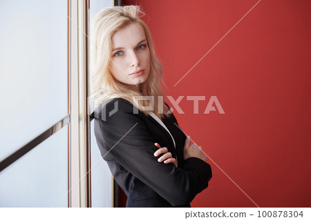 Young adult business woman standing next to the window Young adult business woman standing next to the window 100878304
