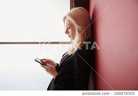 Young adult woman using smartphone at the office 100878305