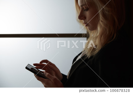 Young adult woman using smartphone at the office Young adult woman using smartphone at the office 100878328