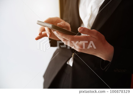 Young adult woman using smartphone next to the white wall Young adult woman using smartphone next to the white wall 100878329