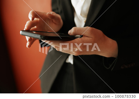 Young adult woman using smartphone next to the red wall Young adult woman using smartphone next to the red wall 100878330