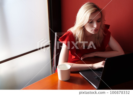 Young adult woman wearing red jumpsuit and using laptop Young adult woman wearing red jumpsuit and using laptop 100878332