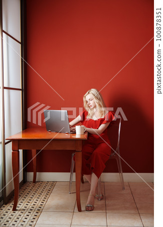 Young adult woman sitting at the table and working on laptop Young adult woman sitting at the table and working on laptop 100878351