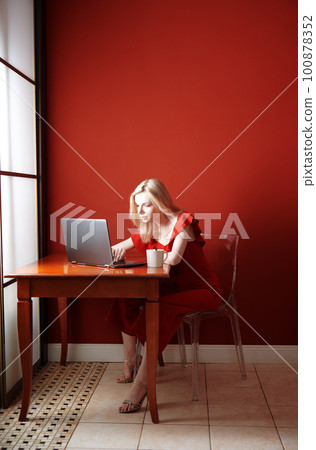 Young adult woman sitting at the table and working on laptop Young adult woman sitting at the table and working on laptop 100878352