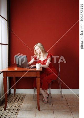 Young adult woman sitting at the table and working on laptop Young adult woman sitting at the table and working on laptop 100878355