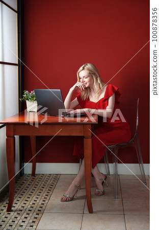 Young adult woman sitting at the table and working on laptop 100878356
