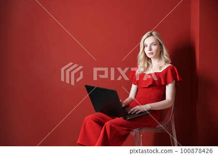 Young adult woman sitting on a chair and working on laptop Young adult woman sitting on a chair and working on laptop 100878426