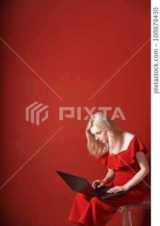 Young adult woman sitting on a chair and working on laptop 100878430