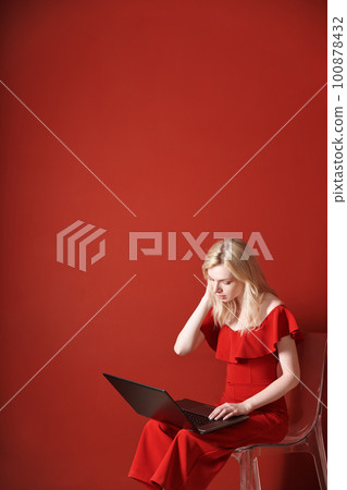 Young adult woman sitting on a chair and working on laptop Young adult woman sitting on a chair and working on laptop 100878432