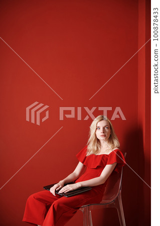 Young adult woman sitting on a chair and holding laptop 100878433