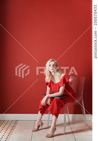 Young adult woman sitting on a chair and holding laptop 100878435