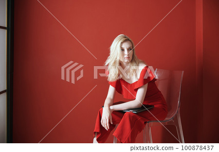 Young adult woman sitting on a chair and holding laptop 100878437