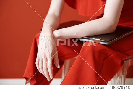 Young adult woman sitting on a chair and holding laptop Young adult woman sitting on a chair and holding laptop 100878548