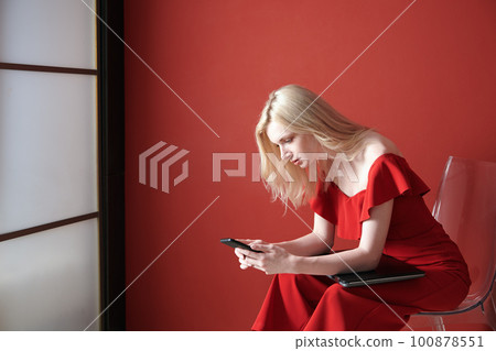 Young adult woman using smartphone and holding laptop 100878551