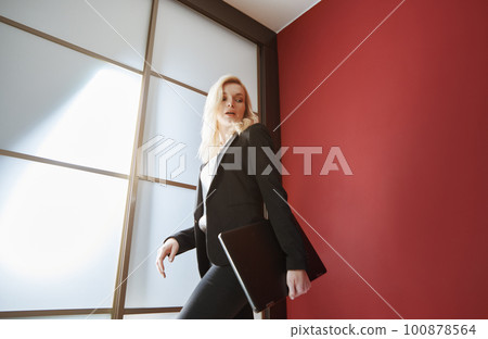 Young adult business woman wearing formalwear and carrying the laptop Young adult business woman wearing formalwear and carrying the laptop 100878564