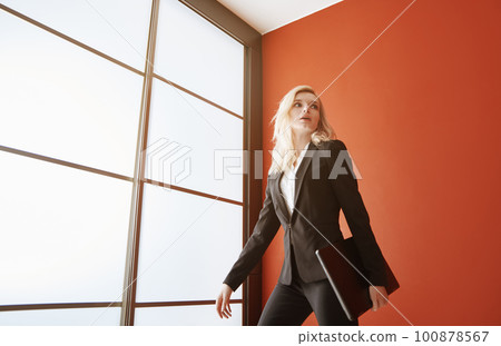 Young adult business woman wearing formalwear and carrying the laptop Young adult business woman wearing formalwear and carrying the laptop 100878567