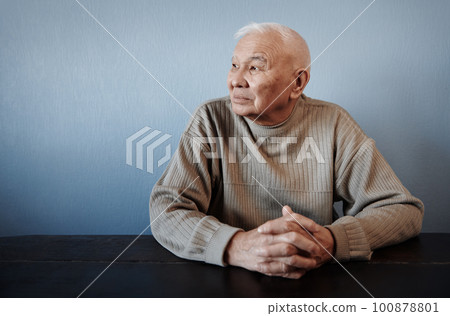 Pensive and thoughtful senior man sitting at the table 100878801