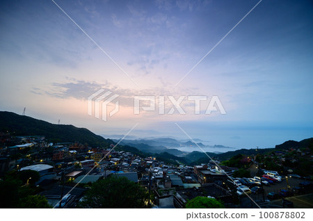 Stunning dusk scenery - vibrant orange sky, dynamic clouds, misty mountains. 100878802