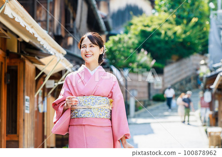 A woman in a kimono sightseeing the streets of Kyoto 100878962