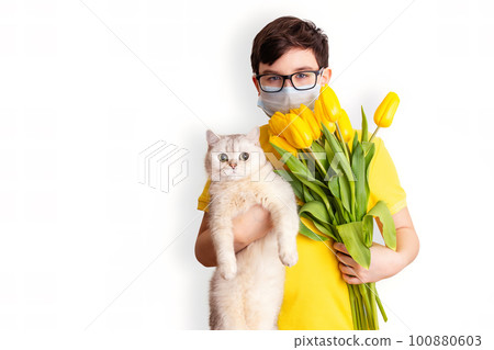 Portrait of a dark-haired boy with medical mask, holding a white cat and a bouquet of yellow tulips Portrait of a dark-haired boy with medical mask, holding a white cat and a bouquet of yellow tulips 100880603