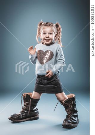 blonde girl plays with big boots. 100881015