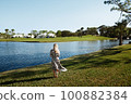 Retro styled woman standing at the lake 100882384