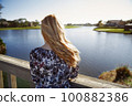Retro styled woman standing on the wooden bridge and looking at the lake 100882386