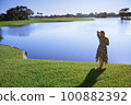 Retro styled woman standing at the lake 100882392