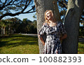 Beautiful woman leaning onto the oak tree 100882393