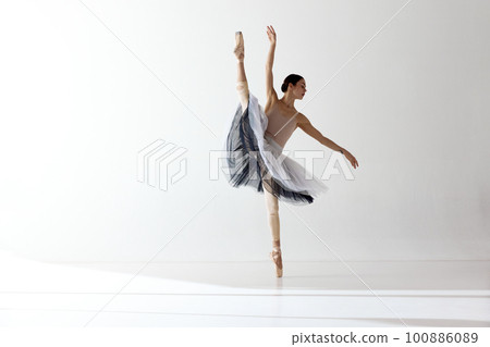 Young and incredibly beautiful ballerina is posing and dancing in a white studio. Classical ballet art 100886089