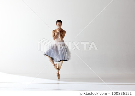 Charming ballerina posing with folded hands smiling with closed eyes over white background 100886131