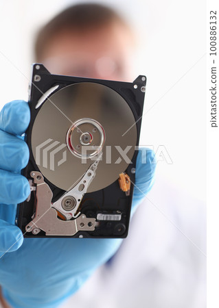 Master in gloves holds hard computer disk closeup 100886132