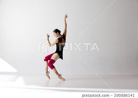Photo of gorgeous ballerina wearing pointe shoes dancing on fingertips over white background 100886141