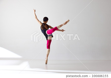 Back view. Ballet dancer standing wearing pointe shoes dancing on fingertips over white background Back view. Ballet dancer standing wearing pointe shoes dancing on fingertips over white background 100886155