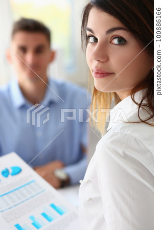 Portrait of woman holding financial chart analytics in hands and discussing with colleague Portrait of woman holding financial chart analytics in hands and discussing with colleague 100886166