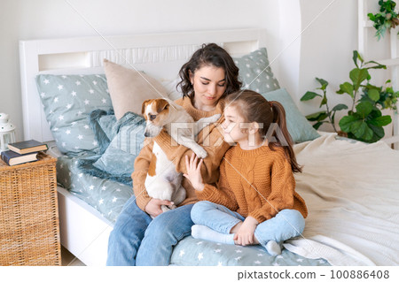 Happy mom and daughter play with their adorable wired Jack Russell Terrier Happy mom and daughter play with their adorable wired Jack Russell Terrier 100886408