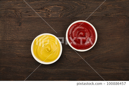Bowls of tomato ketchup and mustard on table Bowls of tomato ketchup and mustard on table 100886457