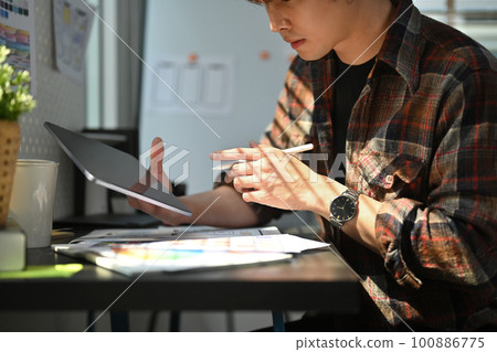 Cropped shot of web developer using digital tablet, working on mobile application software design project at his workstation Cropped shot of web developer using digital tablet, working on mobile application software design project at his workstation 100886775