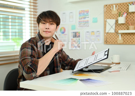 Young creative man ux developer creating sketches of applications for mobile phones at design studio Young creative man ux developer creating sketches of applications for mobile phones at design studio 100887023