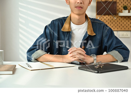 Image of young man in jeans jacket sitting at working desk in home office. Freelance, creative occupation, e-learning concept 100887040
